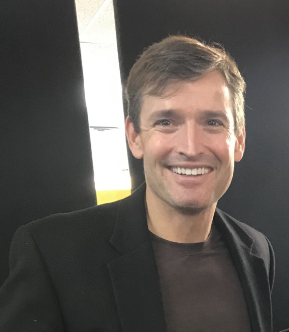 Crane Durham smiling, wearing a dark blazer